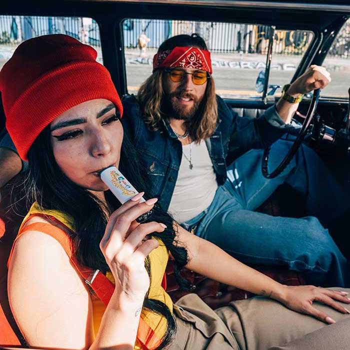 Woman with a red hat and yellow shirt vaping a Cheech and Chong Mambo vaporizer.