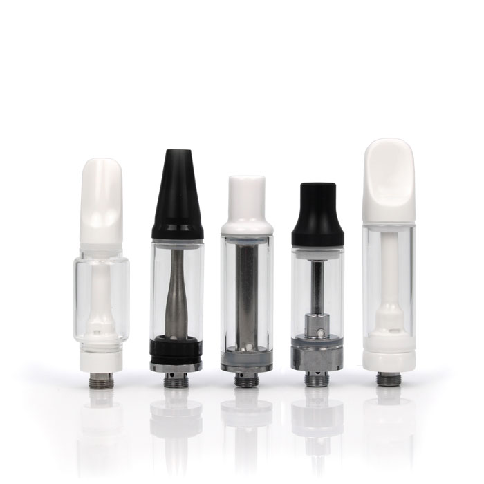 Three white and two black cannabis oil cartridges standing upright.
